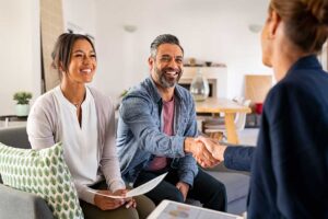 A couple sitting at a kitchen table reviewing documents with a real estate agent.